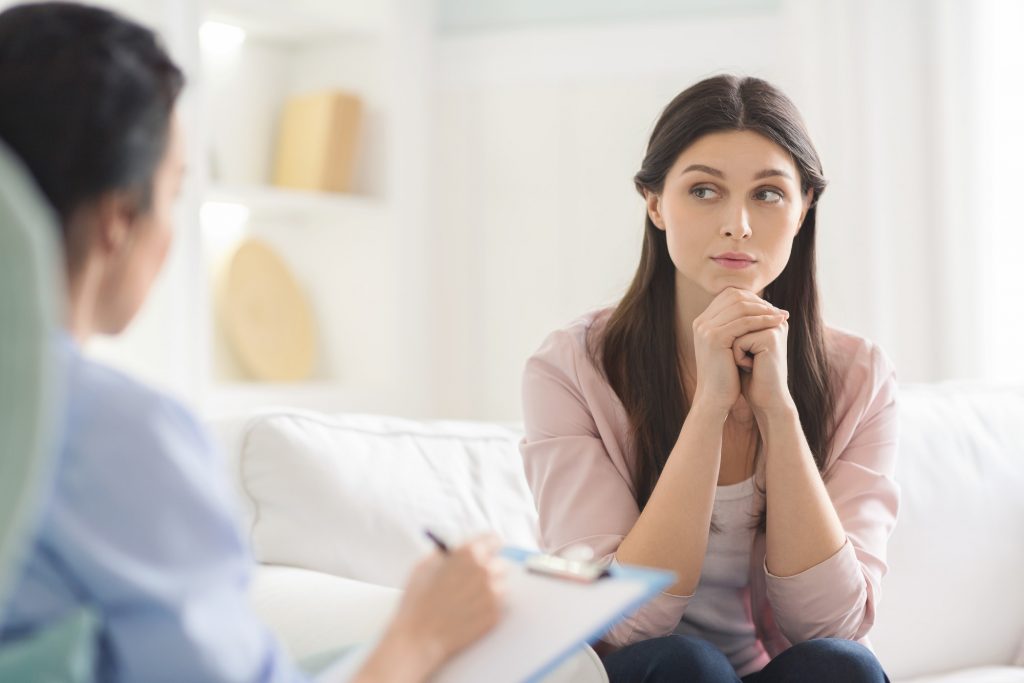 Interested young woman listening carefully to psychotherapist